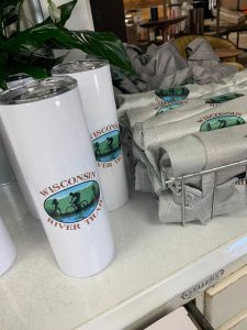 display of Wisconsin River Trail Organization insulated cups and and shirts for sale at Willow and Ivy